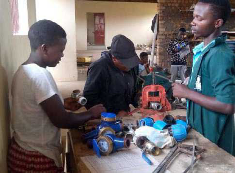 Auszubildende lernen Rohre zuschneiden in unserem Wasserdepartment in Nakaziba